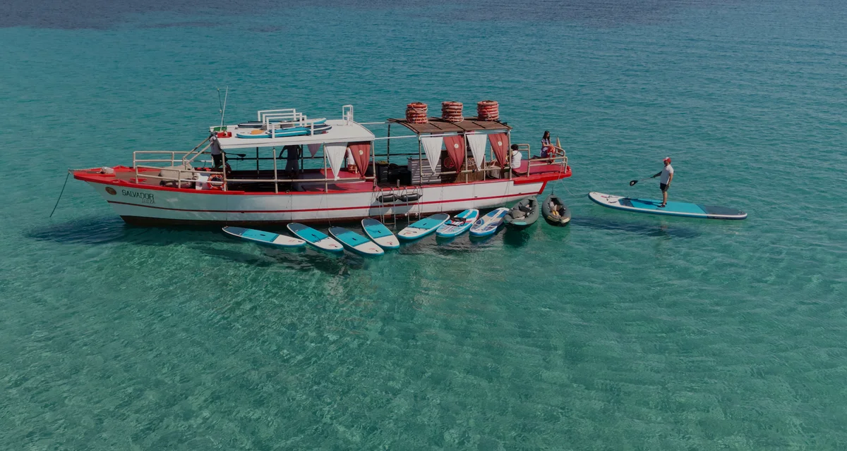 Aerial drone view of Salvador Ibiza anchored in Cala Comte with paddleboards and kayaks